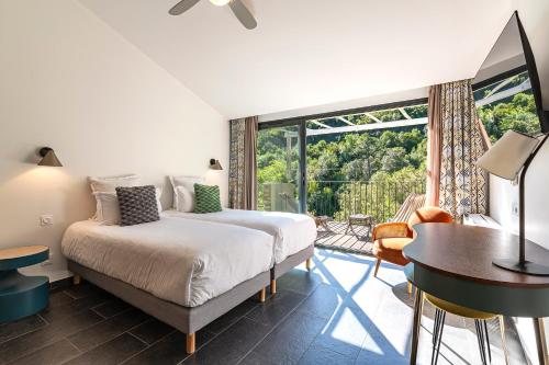 a bedroom with a bed and a desk and a window at Hotel E Caselle - Demeures & Châteaux in Venaco