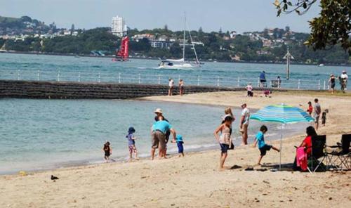 un grupo de personas de pie en una playa en Andelin Guest House, en Auckland