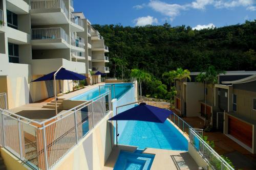 a balcony with a swimming pool and umbrellas at Azure Sea Whitsunday Resort in Airlie Beach