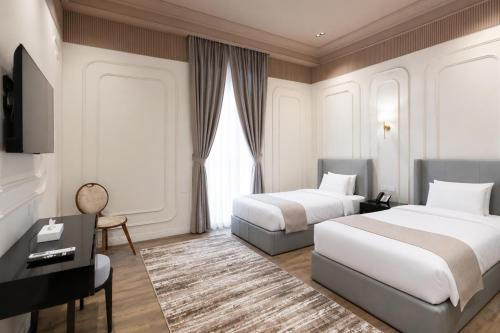 a hotel room with two beds and a desk at Malak Palace Cairo Hotel in Cairo