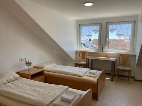 a room with two beds and a desk and a window at Gasthof Kirchberger in Fürth