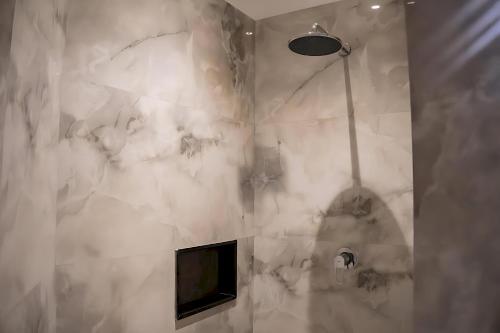 a bathroom with white marble walls and a shower at Hillside Residence E-7 by Paramount Hospitality in Islamabad