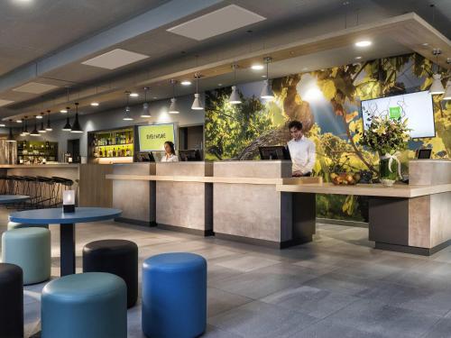 a restaurant with a counter and blue stools at ibis Styles Stuttgart Vaihingen in Stuttgart