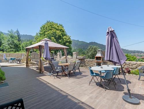 a patio with tables and chairs and an umbrella at Quinta do Avô - Casa de Campo in Terras de Bouro