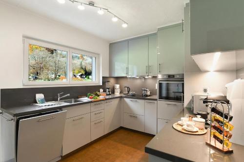 a large kitchen with white cabinets and a window at Casa Mima Chalets in Gerra Verzasca