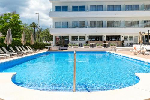 a large swimming pool with chairs and a building at THB Dos Playas - Adults Only in Cala Ratjada