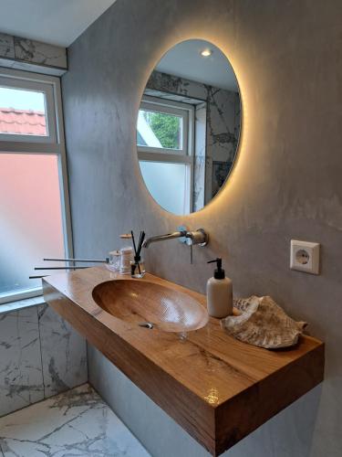 a bathroom with a wooden sink and a mirror at B&B The White House in Westzaan