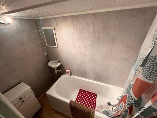 a bathroom with a bath tub with a red stool at Appartement causy in Gonfreville-lʼOrcher