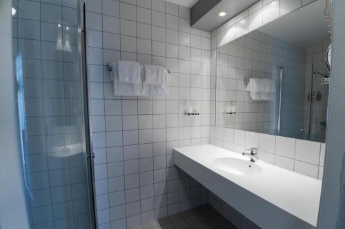 a white tiled bathroom with a sink and a shower at Thorbjørnrud Hotell in Jevnaker