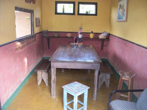 a wooden table in a room with a table and stool at Pousada Beija-Flor in Lavras Novas