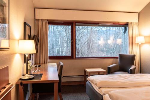 a hotel room with a bed and a desk and a window at Thorbjørnrud Hotell in Jevnaker