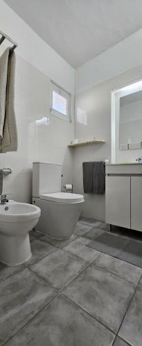 a white bathroom with a toilet and a sink at Balaia Gardens, jardins da Balaia in Albufeira