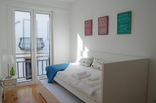 Cama blanca en habitación con balcón en Casa do Chafariz, en Cascais