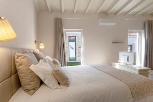 a bedroom with a white bed with pillows and a window at Vila Santa Luzia 6 in Fátima
