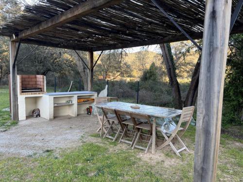 a table and chairs under a pavilion with a table and a grill at E piane in Moltifao