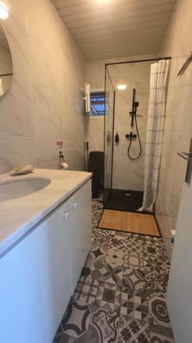 a bathroom with a sink and a shower with a shower curtain at Casa Feia Hostel in Costa da Caparica