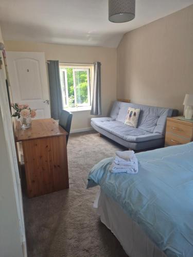 a bedroom with a blue bed and a couch at ACCOMADATION WREXHAM in Wrexham