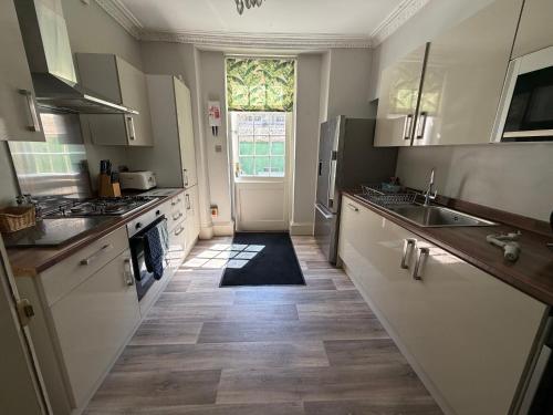 a kitchen with white cabinets and a large window at Dream Stays Bath - Trim Street Townhouse with Hot tub in Bath