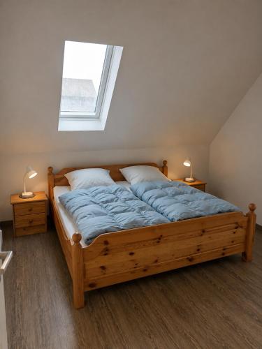 a bedroom with a wooden bed with a window at Ferienwohnung nahe Nordseeküste in Großheide
