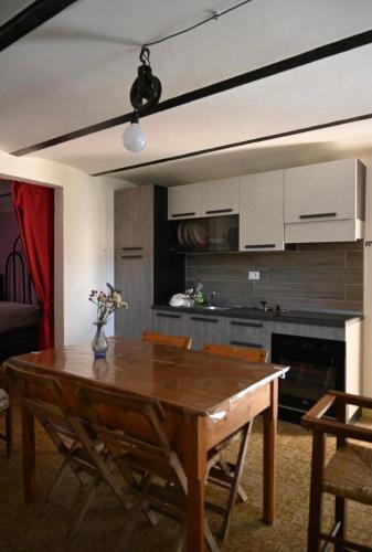 a living room with a wooden table and a kitchen at La casa di Mastro Ivetto in Arcevia