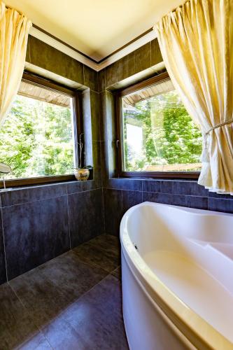 a bath tub in a bathroom with two windows at Breite Privée Forest and Pool Retreat in Sighişoara