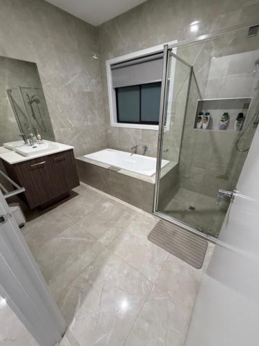 a bathroom with a shower and a tub and a sink at Private Room in Rockbank in Rockbank