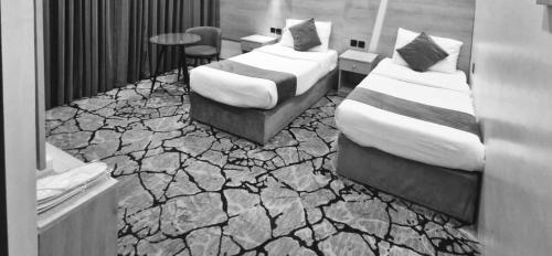 two beds in a room with a stone floor at فندق ميراب الروضة in Al Khansāk