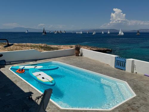 a swimming pool with a kayak and a boat on it at NV seafront Villa with private pool & NV seafront luxury suites no pool acces - Aegina in Áyioi
