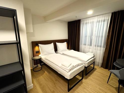 a bedroom with a bed with white sheets and a window at Factory Suites in Prague