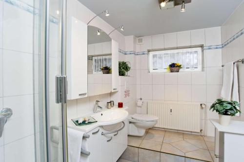 ein weißes Bad mit einem WC und einem Waschbecken in der Unterkunft Deich-Residenz App. 1 in Grömitz