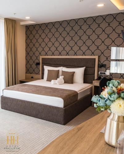 a bedroom with a large bed with a wall at Hotel Kragujevac in Kragujevac