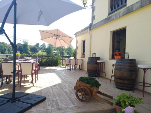 eine Terrasse mit Tischen, Stühlen und einem Sonnenschirm in der Unterkunft Hotel Salldemar in Santillana del Mar