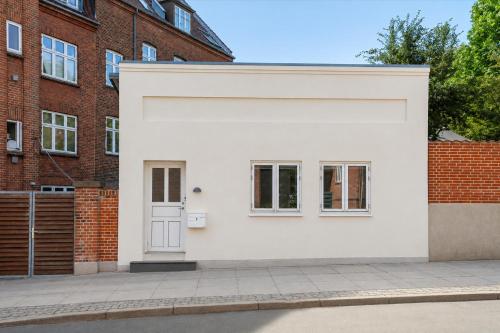 a white house with a door and a brick building at Det Gamle Vaskeri - Historical Apartment in Horsens in Horsens