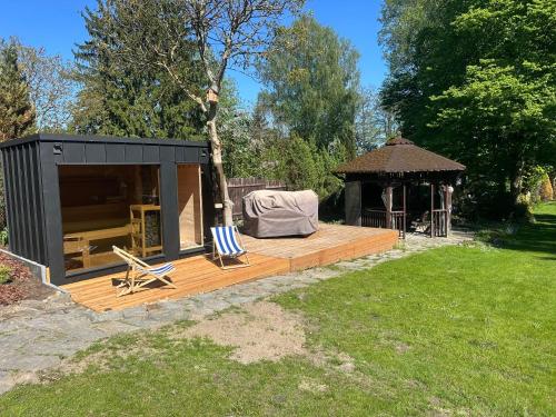 a black building with a deck and a gazebo at POGO dom nad Narwią - 4 sypialnie, duża sauna, balia, pomost, plac zabaw in Pogorzelec