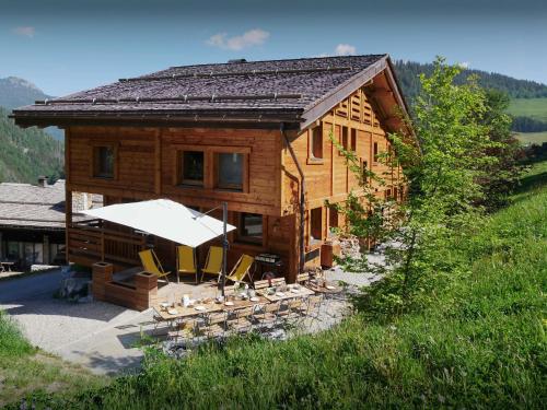 a wooden house with chairs and an umbrella at Chalet Limanosa - OVO Network in La Clusaz