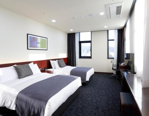 Eumseongにあるゲオサン ホテルのベッド2台とテレビが備わるホテルルームです。