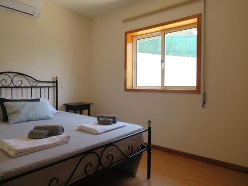a bedroom with a bed with towels and a window at Casal do Porto - Um refugio de férias in Vila Verde