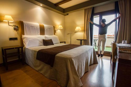 a woman standing next to a bed in a hotel room at Hotel Spa Balfagon in Cantavieja