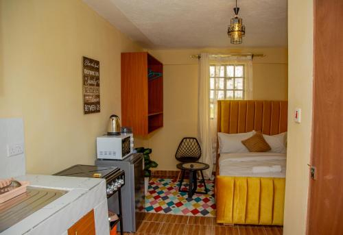 a small room with a bed and a kitchen at Mustard studio with free WI-FI in Nanyuki