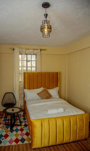 a bedroom with a large yellow bed with a chandelier at Mustard studio with free WI-FI in Nanyuki