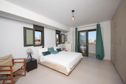 a bedroom with a bed and a chair and windows at Lefkada Town Condo in Lefkada