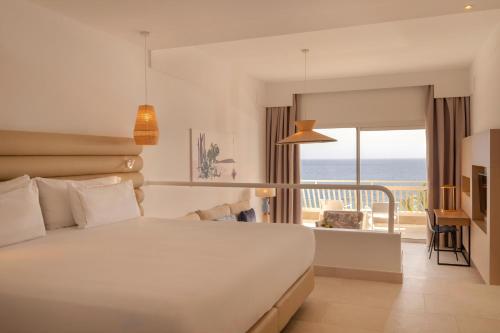 a bedroom with a bed and a balcony with the ocean at Plus Fariones Suite Hotel in Puerto del Carmen