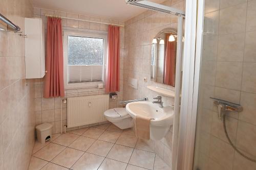 a bathroom with a sink and a toilet and a window at Bernstein Mare-Comfort Wohnung 5 in Büsum