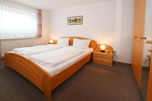 a bedroom with a bed with white sheets and two lamps at Bernstein Mare-Comfort Wohnung 5 in Büsum