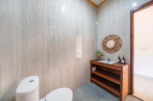 a bathroom with a toilet and a sink and a mirror at The Pulau Bungalow in Nusa Lembongan