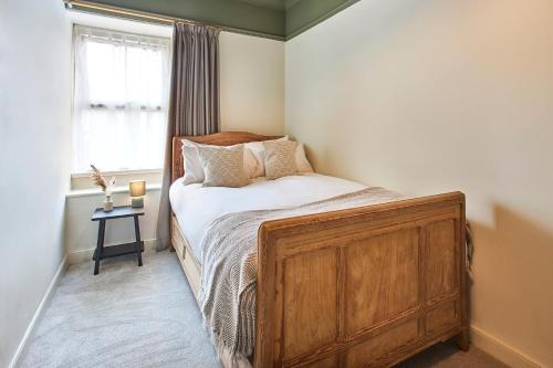 a bedroom with a bed with a wooden dresser and a window at Alnwick 2 Bed Cottage Stay, Joe's Cottage in Alnwick