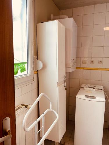 a small kitchen with a white refrigerator and a toilet at Les Volets Blancs in Étaples