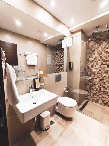 a bathroom with a sink and a toilet and a shower at Hotel Kragujevac in Kragujevac