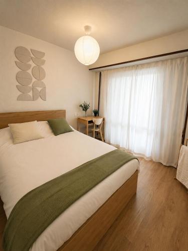 a bedroom with a large white bed and a window at Letras del Tormes in Salamanca