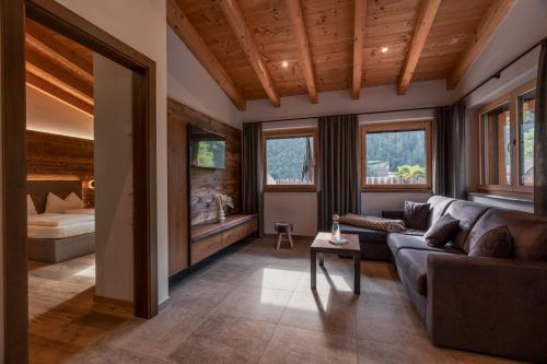 a living room with a couch and a bed at Chalet Resort Innerluferhof in Rifiano